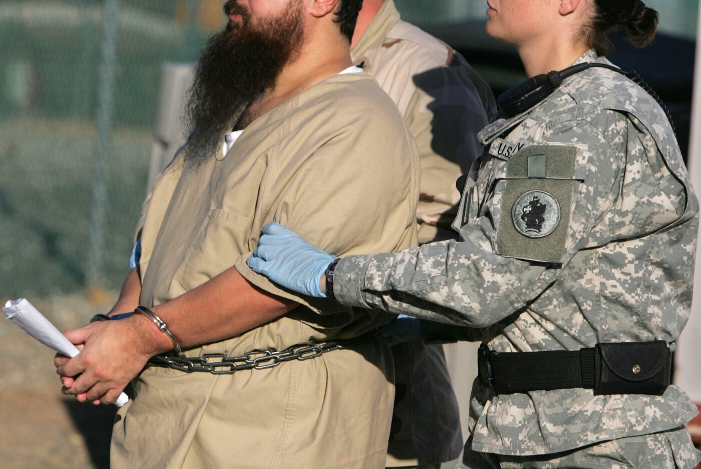 A shackled detainee is transported by guards, including a female soldier, at Camp Delta detention center, Guantanamo Bay U.S. Naval Base, Cuba, in this photo from December 2006.
