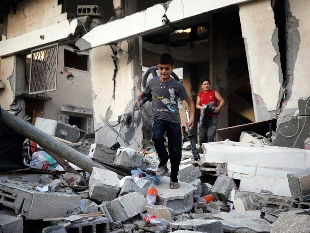 Meninos palestinos buscam pertences em uma casa danificada. (Foto: Finbarr O'Reilly / Reuters)