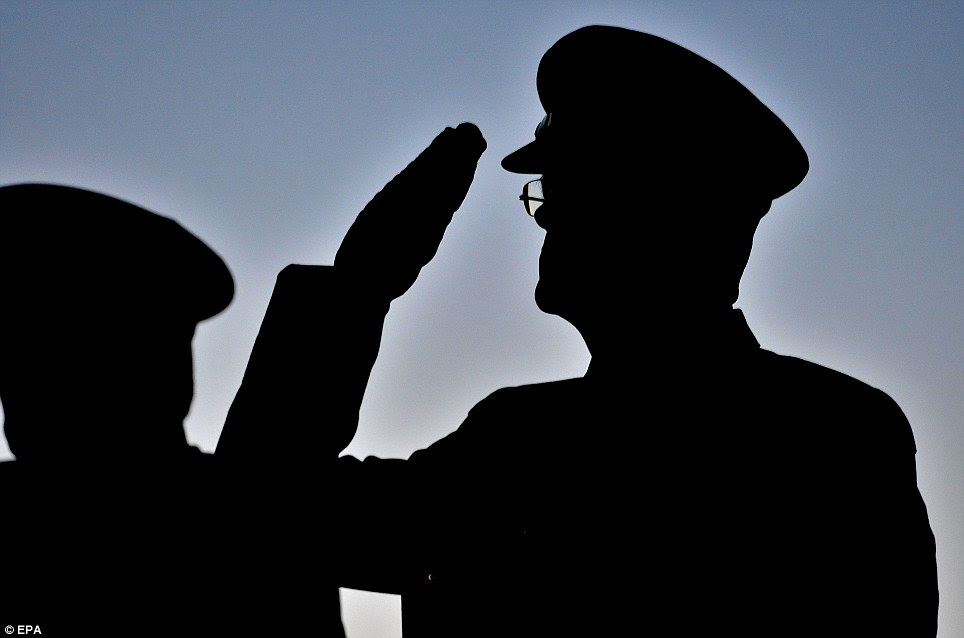 The silhouette of an Australian armed forces officer is captured as he salutes during the ANZAC Day dawn service at the Shrine of Remembrance in Melbourne, Australia