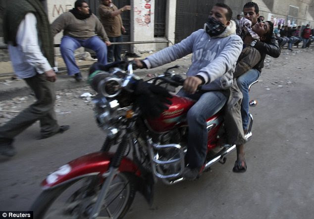 Ambulance bike: Protesters carry an injured comrade after the clashes with police yesterday