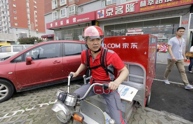 Richard Liu, CEO and founder of China's e-commerce company JD.com, rides an electric tricycle as he leaves a delivery station to deliver goods for customers to celebrate the anniversary of the founding of the company, in Beijing, June 16, 2014. REUTERS/Jason Lee