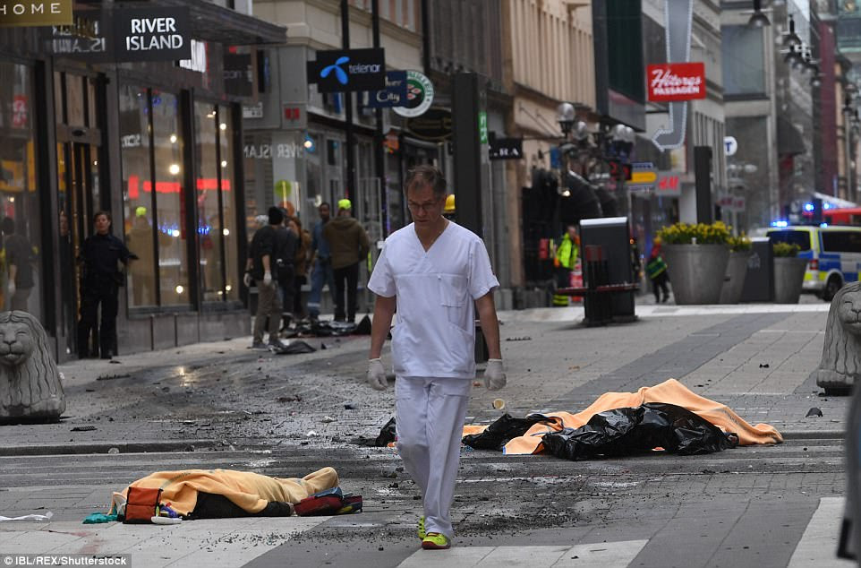A man in scrubs was seen walking along the street with several emergency services people behind him. Several bodies were seen covered by blankets