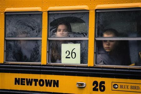 Children look out through condensation on the windows of a school bus numbered 26 as it pulls into Newtown High School in Newtown, Connecticut December 18, 2012. REUTERS-Lucas Jackson