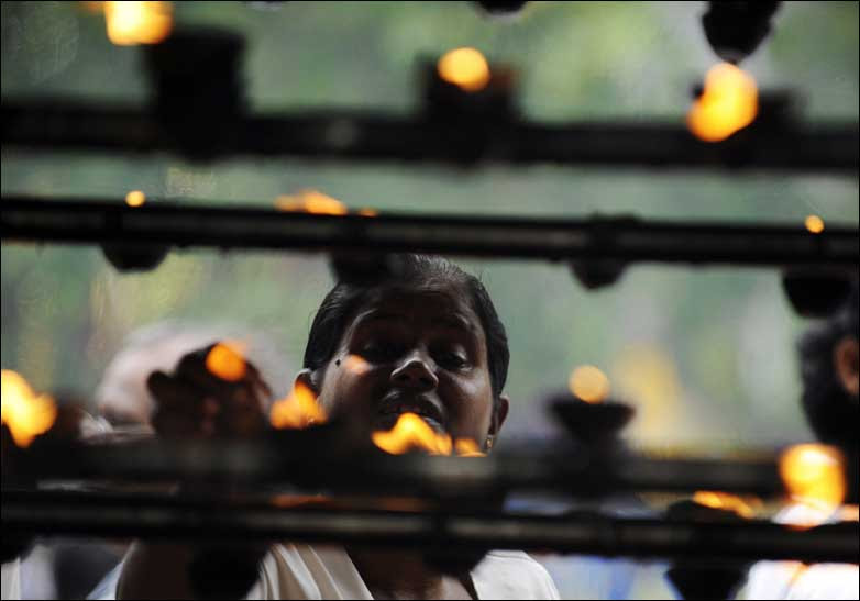 Sri Lankan Buddhists light oil lamps 