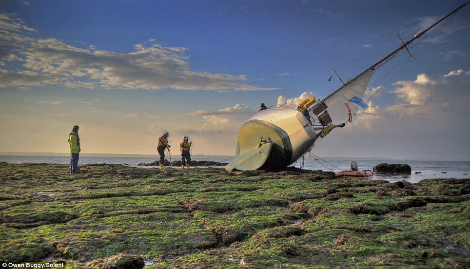 Long wait: Rescue crews came to the aid of the Bermudan-rigged sloop but the crew of six had to wait until the early hours of this morning until high tide to refloat