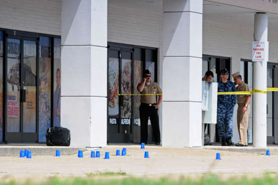 Reserve Recruitment personnel stand outside a Navy recruiting building as the area is cordoned off with blue shell casing markers in the parking lot on Thursday, July 16, 2015 in Chattanooga, Tenn.  At least two military facilities in Tennessee were attacked in shootings Thursday, including one at a Navy recruiting building, officials said.