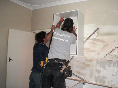 Installing first wall cabinet in kitchen