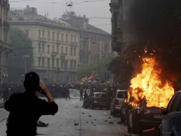 Um carro queima durante protesto contra a Exposição Universal em Milão, na Itália (Foto: Luca Bruno/AP)