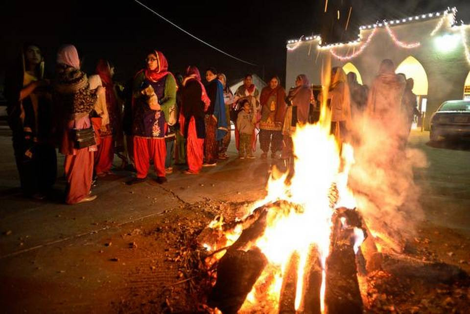 People gather around the fire during Lohri, a Punjabi festival, in Livingston on Tuesday.