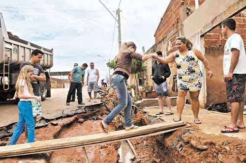 Moradores se arriscam para chegar em casa no Condomínio Por do Sol: chuva provocou erosão e inundou três residências (Marcelo Ferreira/CB/D.A Press)