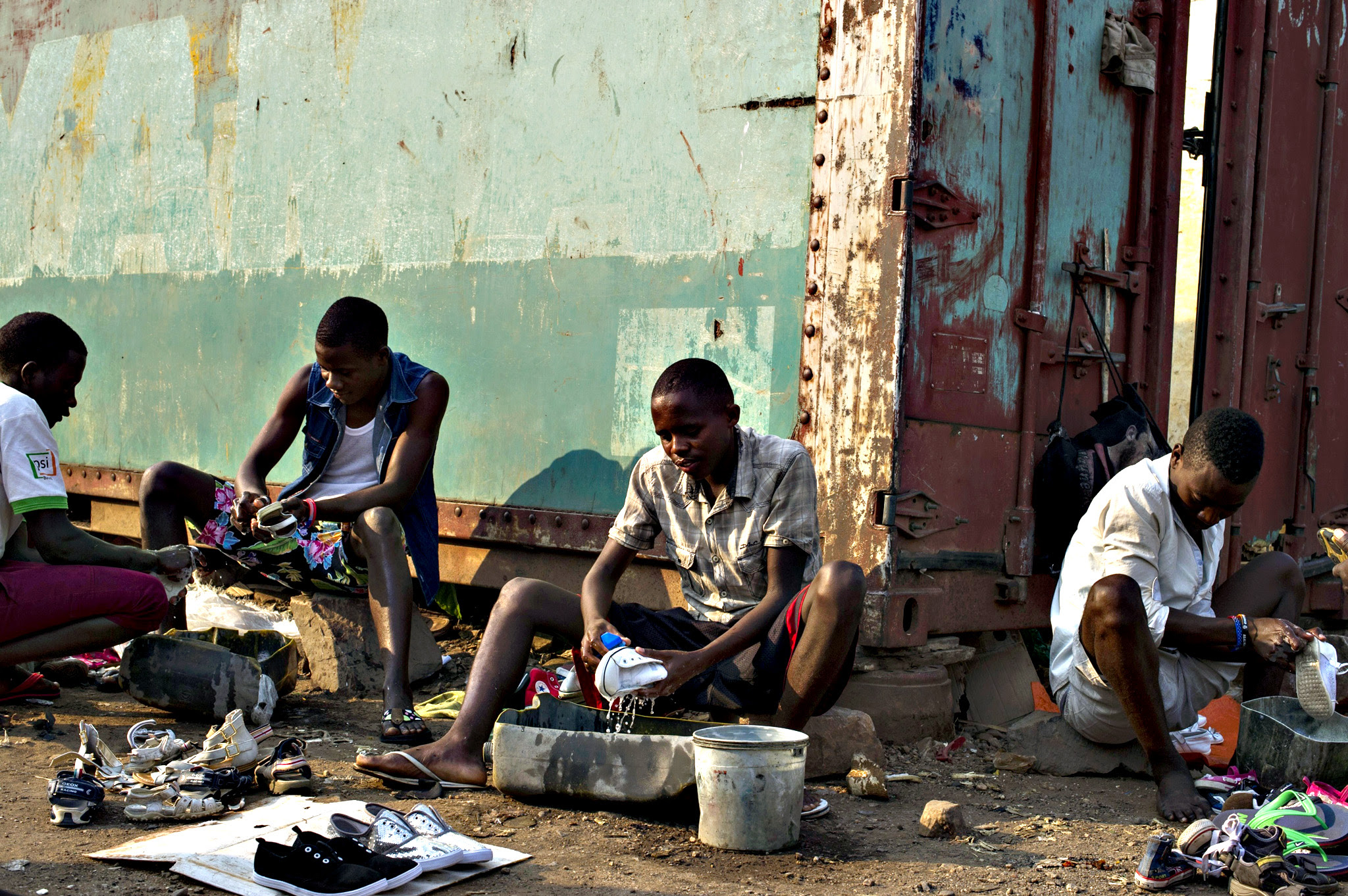 Young men clean second-hand shoes to sell them on a market in Bujumbura on July 24, 2015. Burundian President Pierre Nkurunziza is set to win a controversial third term in office, but analysts say his victory will be hollow, with the country divided, isolated and facing aid cuts