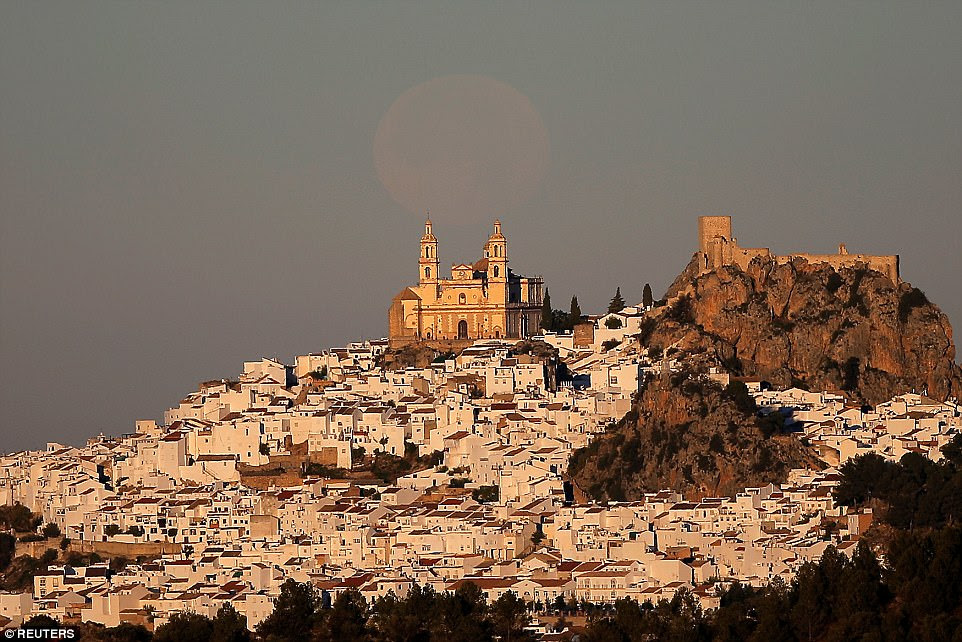 The supermoon is pictured setting over the church of Nuestra Senora de la Encarnacion at dawn in Olvera, near Cadiz, southern Spain