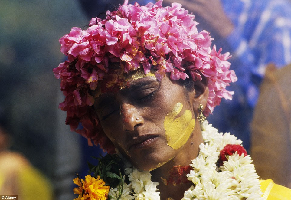 A Hindu pilgrim in a deep trance as she is about to have a sharp spear inserted through both of her cheeks as part of the festival in South India