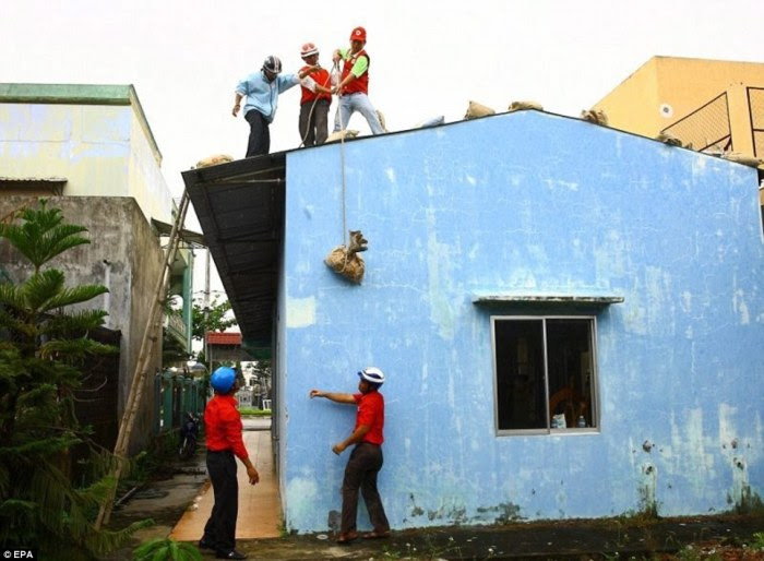 Properties: Volunteers place sand bags on the roof of a house