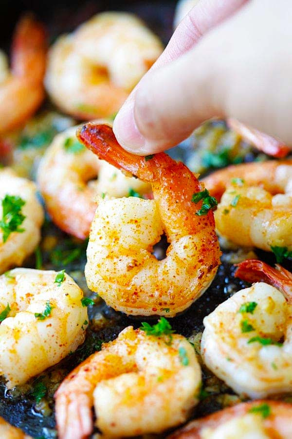Picking up garlic shrimp with fingers.