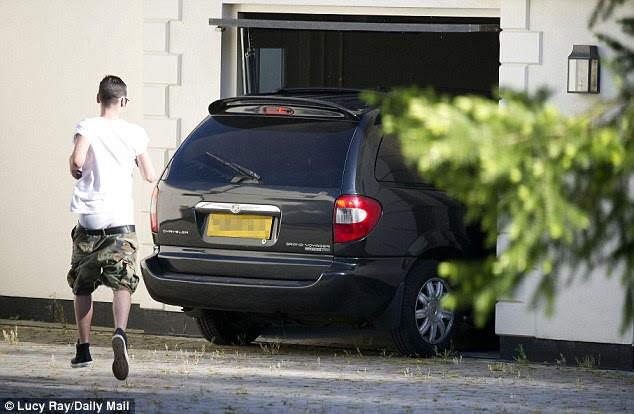 Return: Tulisa arrived back at her home at 6.30pm tonight in a black Chrysler with blacked-out windows, and was driven straight into a garage, so she could not be seen. Her PA Gareth Varey is pictured running behind it