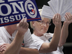 Melissa Fults, treasurer for Arkansans for Compassionate Care, holds up cards at the back of a news conference in Little Rock, Ark., with the names of doctors she says support a ballot issue that would legalize medical marijuana.