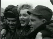 Marilyn Monroe steps from US military helicopter, military personnel greet and take photographs with her, Monroe waves to troops from inside car before being driven away, Korea; Feb 54