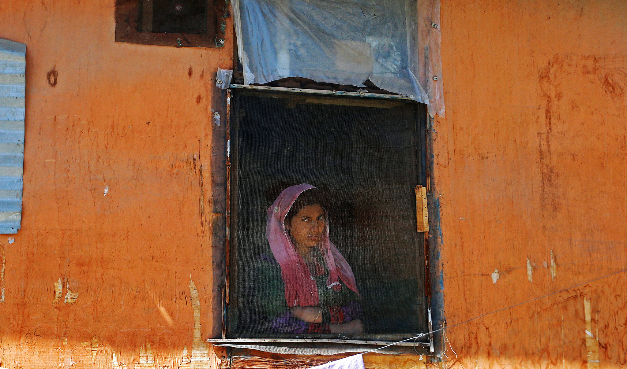 A woman looks out from a window in Srinagar,during a protest against the recent killings in Kashmir