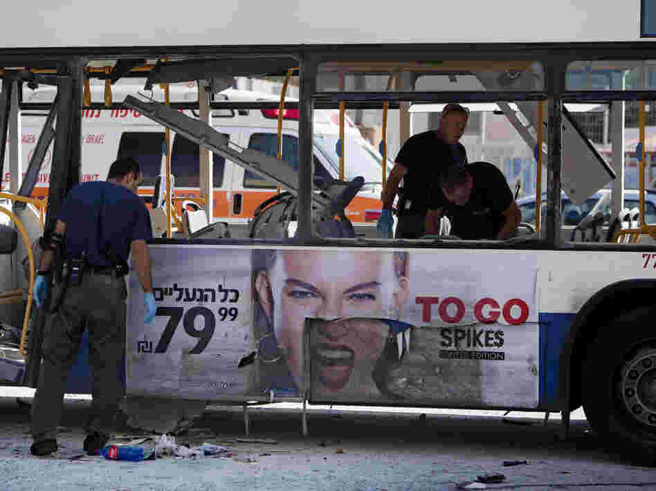 Israeli police officers examine a blown up bus at the site of a bombing in Tel Aviv on Wednesday.