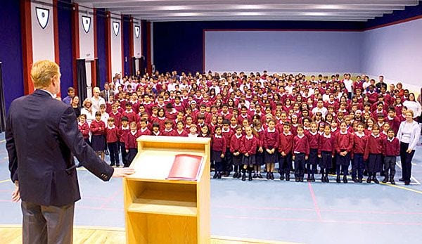 A1ENDA Headmaster takes pupils and staff assembly in modern school hall