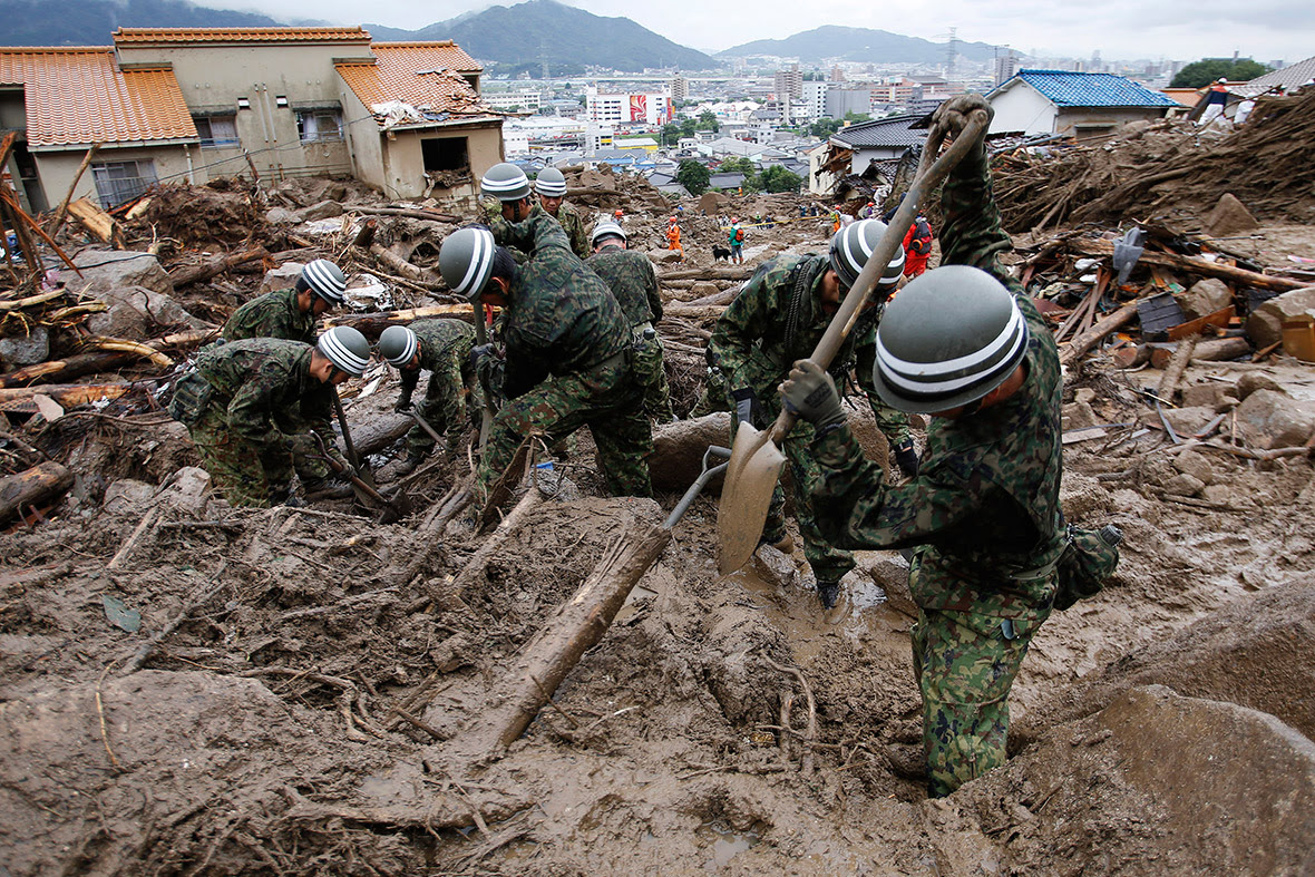 Japanese soldiers search for survivors and bodies in the mud at a site where a landslide swept through a residential area in Hiroshima