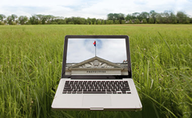 A computer in a field with an image of a city