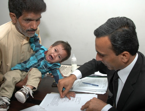 5.abr.2014 - Foto tirada em 3 de abril mostra um policial paquistanês pegando as digitais do bebê Muhammad Mosa, que tem nove meses de vida. Ele foi acusado de tentativa de assassinato durante uma operação da polícia