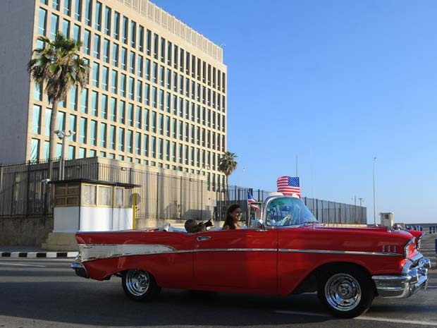 Carro com bandeira dos Estados Unidos passa em frente ao prédio da embaixada do país em Havana nesta segunda-feira (20) (Foto: AFP PHOTO/YAMIL LAGE)