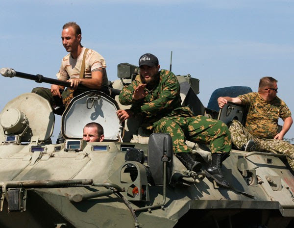 Vestidos com roupas militares, homens em veículos de guerra usam estrada perto da fronteira com a Ucrânia. (Foto: Alexander Demianchuk/Reuters)