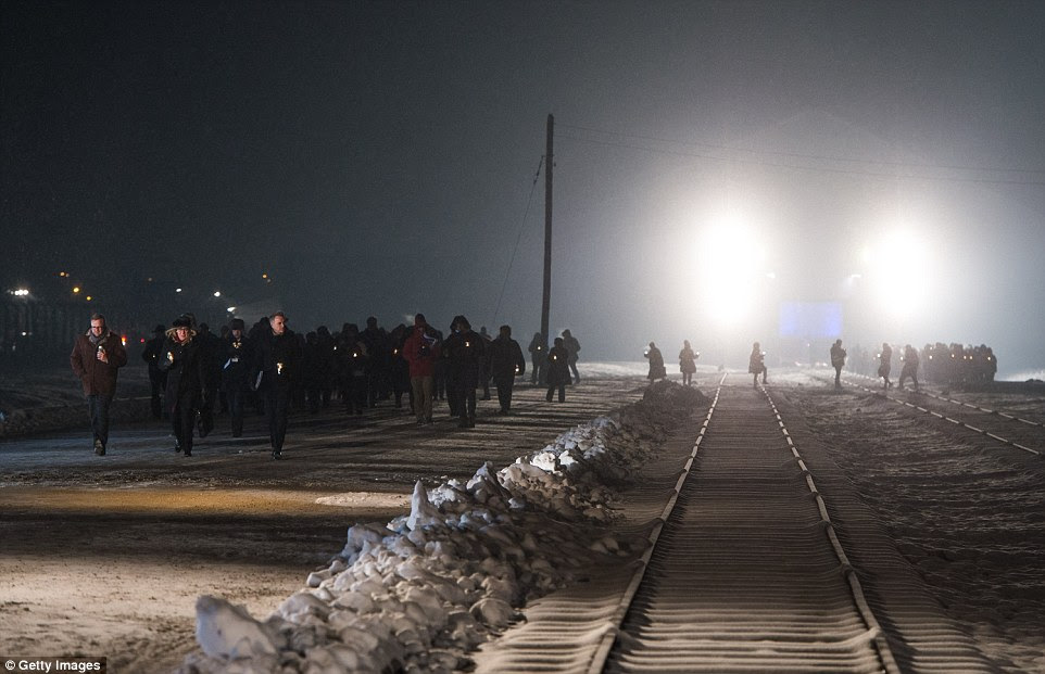 Attending dignitaries and survivors of the Holocaust walk past the train tracks once used to ferry people into the death camp