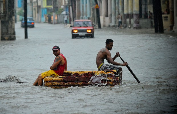 Homens usam barco improvisado para circular por rua inundada nesta quarta-feira (29) em Havana (Foto: Yamil Lage/AFP)