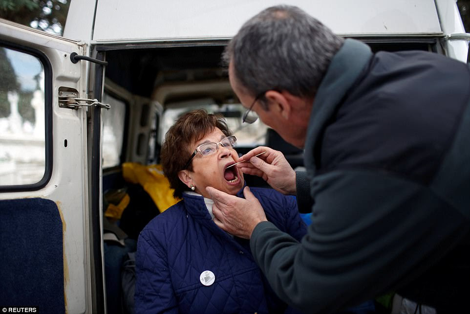 Fernando Serrulla, forensic anthropologist member of the Aranzadi Science Society takes a saliva sample from Julia Merino for a DNA test during the exhumation
