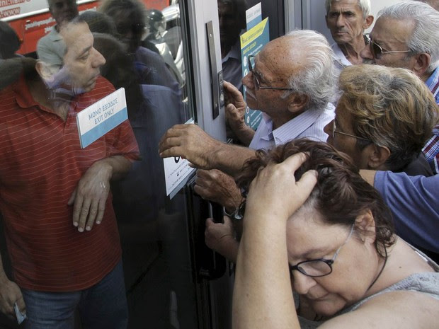 Pensionistas aguardam em frente a uma agência fechada do Banco Nacional da Grécia, na esperança de receberem suas pensões, e discutem com um funcionário do banco em Iraklio, na ilha de Creta (Foto: Stefanos Rapanis/Reuters)