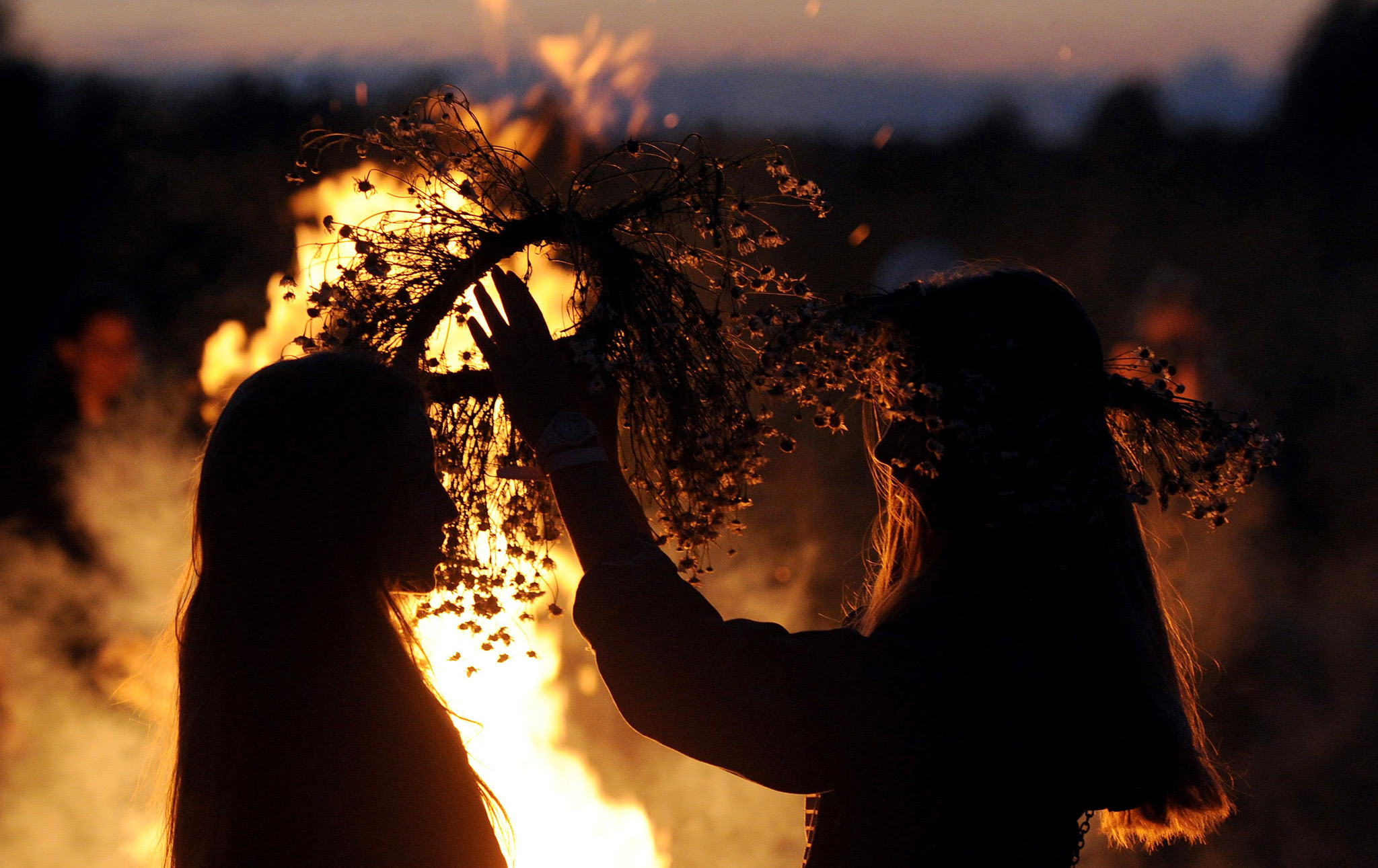 Two girls put traditional wreaths near a bonfire as they take part in the Ivan Kupala Night celebration, a traditional Slavic holiday, outside the small town of Turov, some 270 km south of Minsk, on July 6, 2016.  People celebrate Kupala Night with bonfires that last throughout the night with some leaping over the flames as it is believed that the act of jumping over the bonfire cleanses people of illness and bad luck. / AFP PHOTO / SERGEI GAPONSERGEI GAPON/AFP/Getty Images