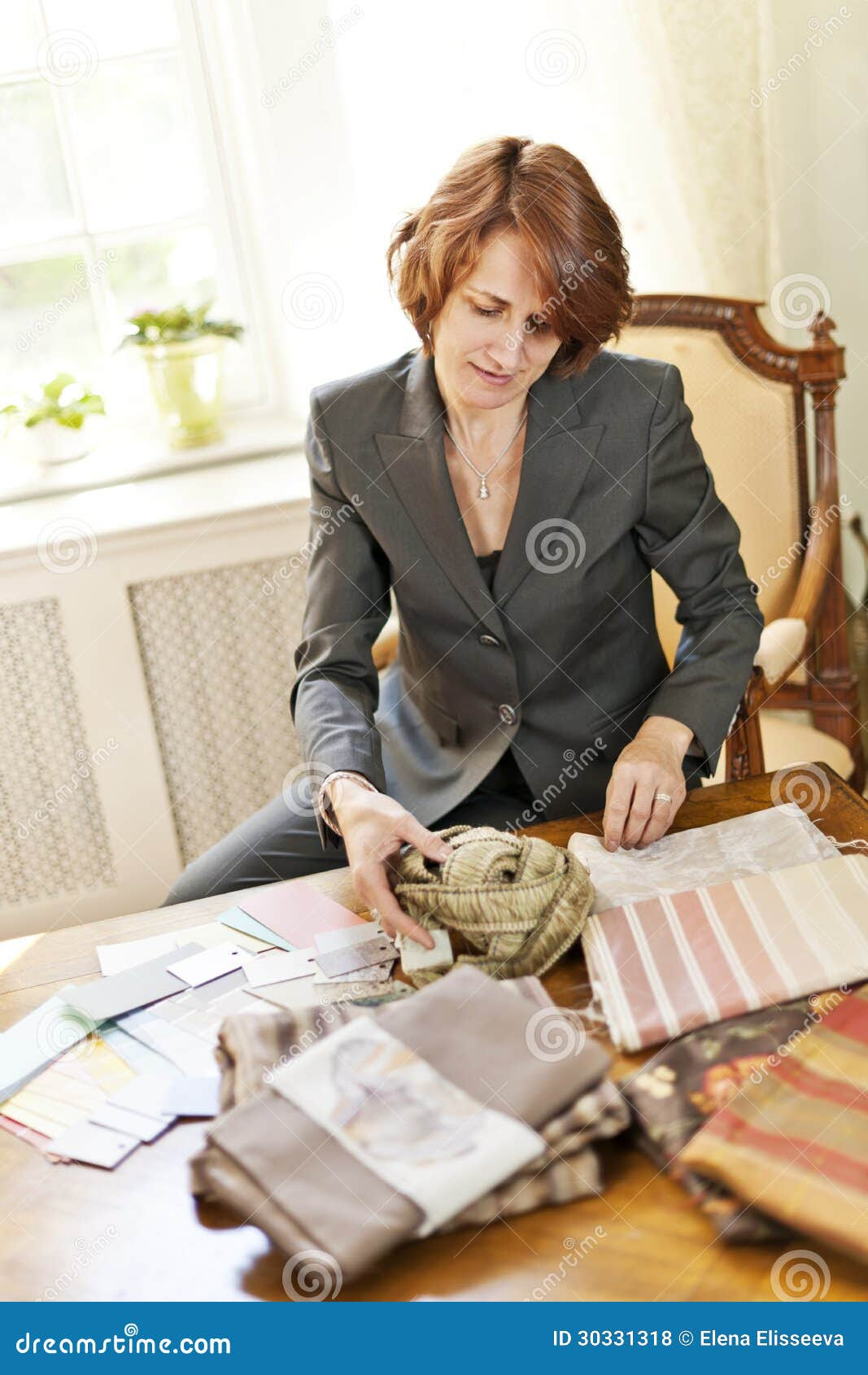 Female interior designer choosing from fabric samples sitting at desk.