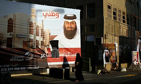 A Bahraini woman walks past election campaign billboards near Manama