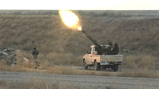 In this photo released on June 26, 2015, by a website of Islamic State militants, an Islamic State militant fires an anti-aircraft gun from the back of a pickup truck in Hassakeh city, northeast Syria (Militant website via AP) 