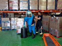 Un bombero se viste con el traje de protección química ayudado por un compañero en la fábrica de Cintruénigo.