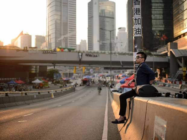 Manifestante pró-democracia observa o nascer do sol de uma rua vazia no distrito Admiralty de Hong Kong. Poucos ativistas permanecem nas ruas. (Foto: Ed Jones / AFP Photo)