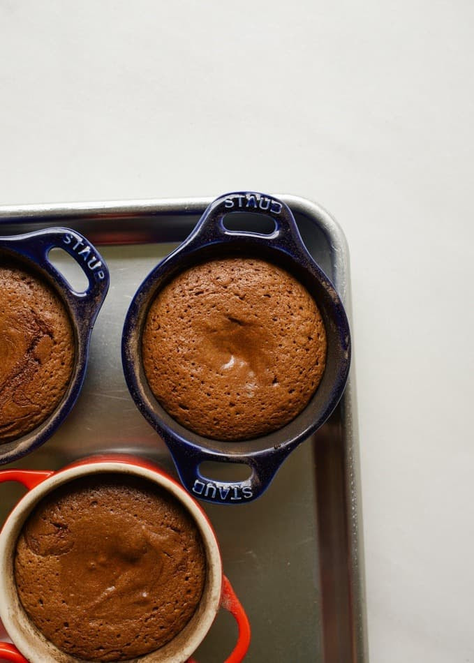 Molton Caramel Chocolate Cakes by Wood and Spoon. These are rich dark chocolate Lava cakes with a homemade salted caramel sauce in the center. Each individual dessert prepared in ramekins are baked until the gooey centers are melted and the cake is baked. Each treat is served with fresh whipped cream. Find the recipe and learn more about this fancy decadent dinner party finisher at thewoodandspoon.com by Kate Wood