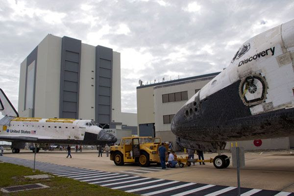 KSC workers towing Discovery wait while Atlantis heads for OPF-1 on March 9, 2012.