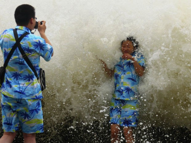 Turista tira foto com onda na China. Ondas chegaram a nove metros de altura após passagem de tufão pelo país. (Foto: Reuters/Stringer )