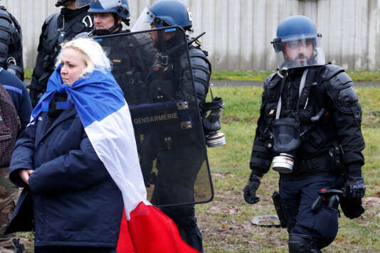Une gardienne de prison porte un drapeau français alors qu’elle se tient près des gendarmes  devant la prison de Maubeuge lors d’une manifestation nationale, le 24 janvier.