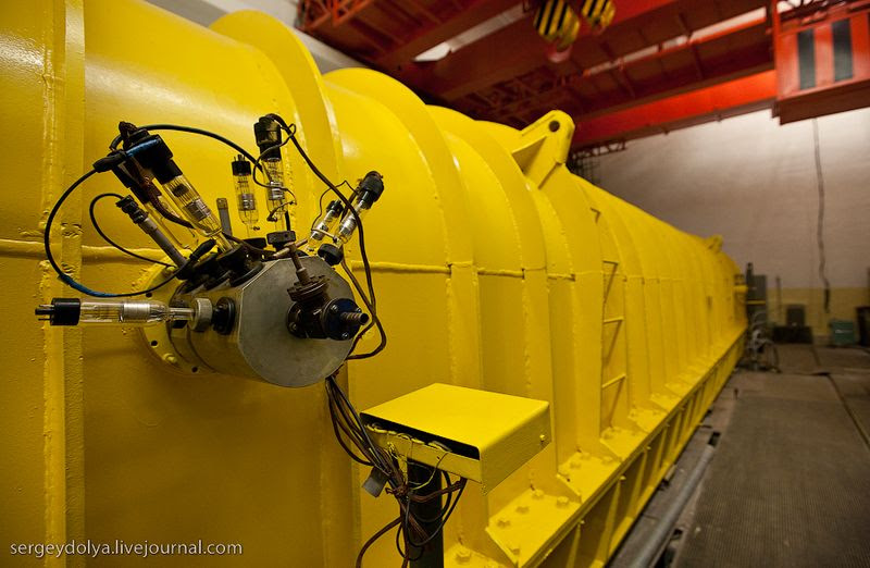 Из кожуха линейного ускорителя (ЛУ-20) торчат вакуумные лампы. Для того, чтобы частицы не тормозились от столкновений с молекулами воздуха, внутри ускорителя воздух откачан практически полностью: