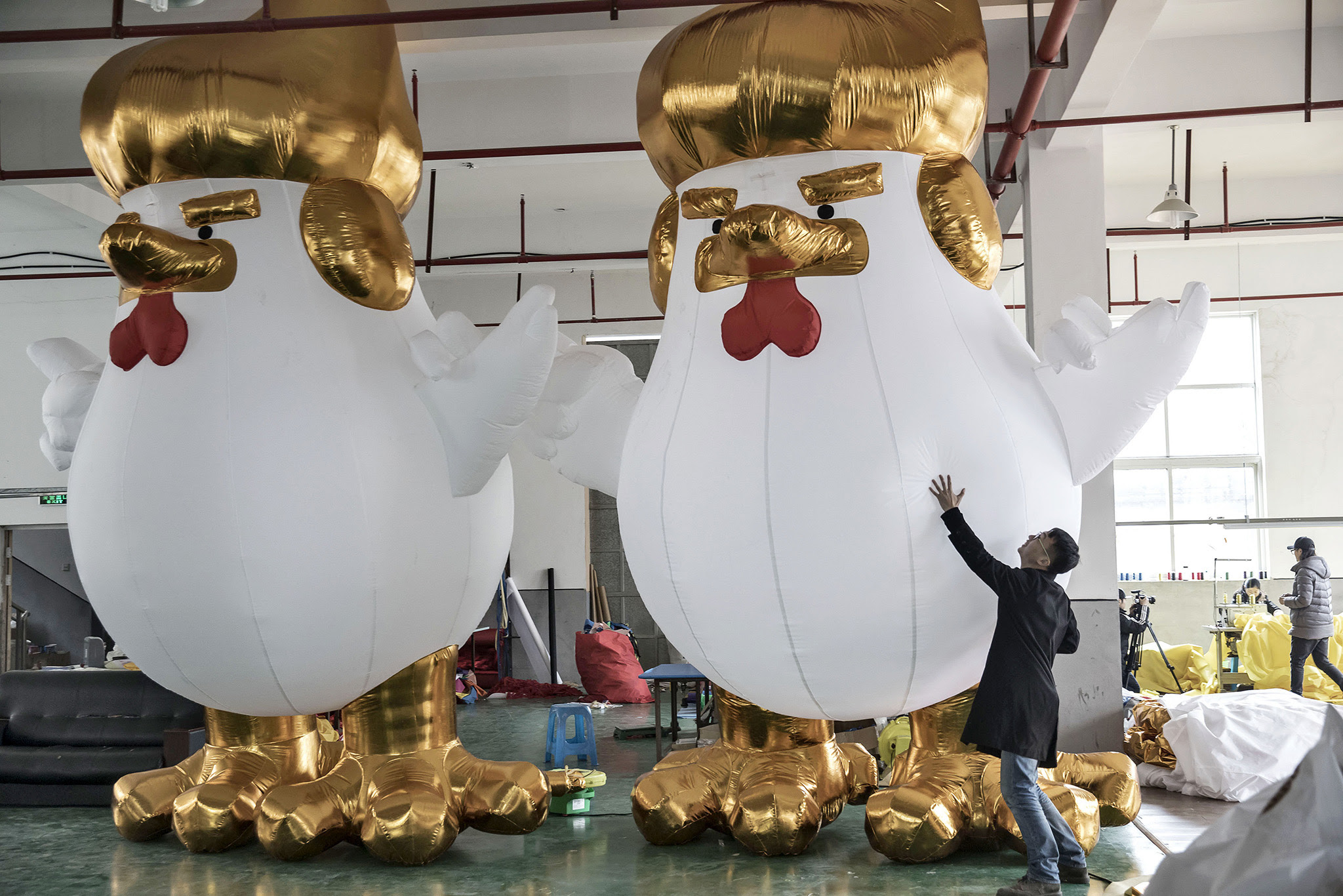 A worker handles an inflatable chicken, bearing a likeness to U.S. President-elect Donald Trump and produced ahead of the Lunar New Year of the Rooster, at a Caile Inflatables Products Co. factory in Jiaxing, China, on Thursday, Jan. 12, 2017. China's state media rebuffed a suggestion by Trump's nominee for secretary of state that Beijing must be denied access to reclaimed reefs in the disputed waters of the South China Sea. Photographer: Qilai Shen/Bloomberg