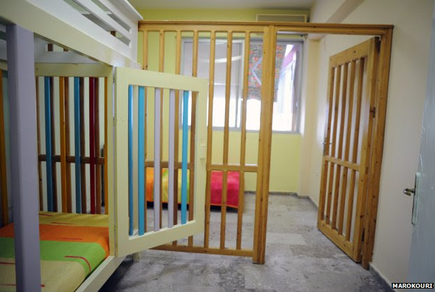 A caged bed and wooden bars separating a section of a room - some of the wood has been painted