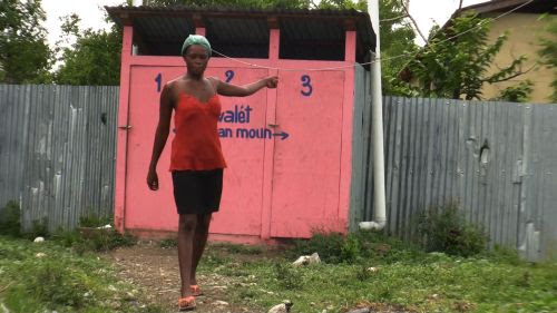 Woman at Leogane camp saying the latrines behind her are full and smell foul. / Credit:Haiti Grassroots Watch