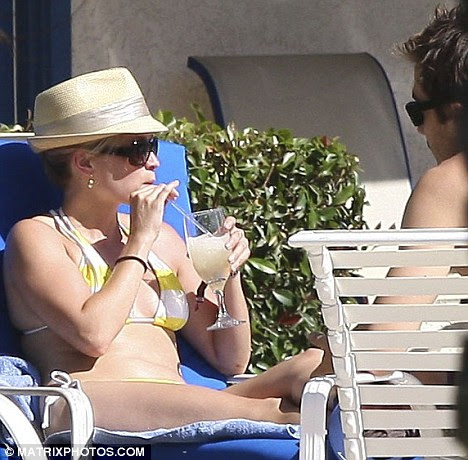 Unlikely bikini babe: Reese Witherspoon sips on a Pina Colada as she chats to boyfriend Jake Gyllenhaal at the Coachella Festival