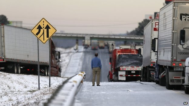 A man stood on a frozen roadway along Interstate 75 in Macon, Georgia, on 29 January 2014 